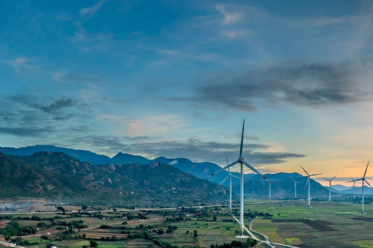 Vibrant aerial view of wind turbines in lush Vietnamese landscape at sunset, showcasing renewable energy.