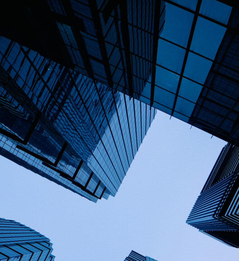 Low angle view of sleek, modern skyscrapers with glass facades forming geometric pattern against the sky.