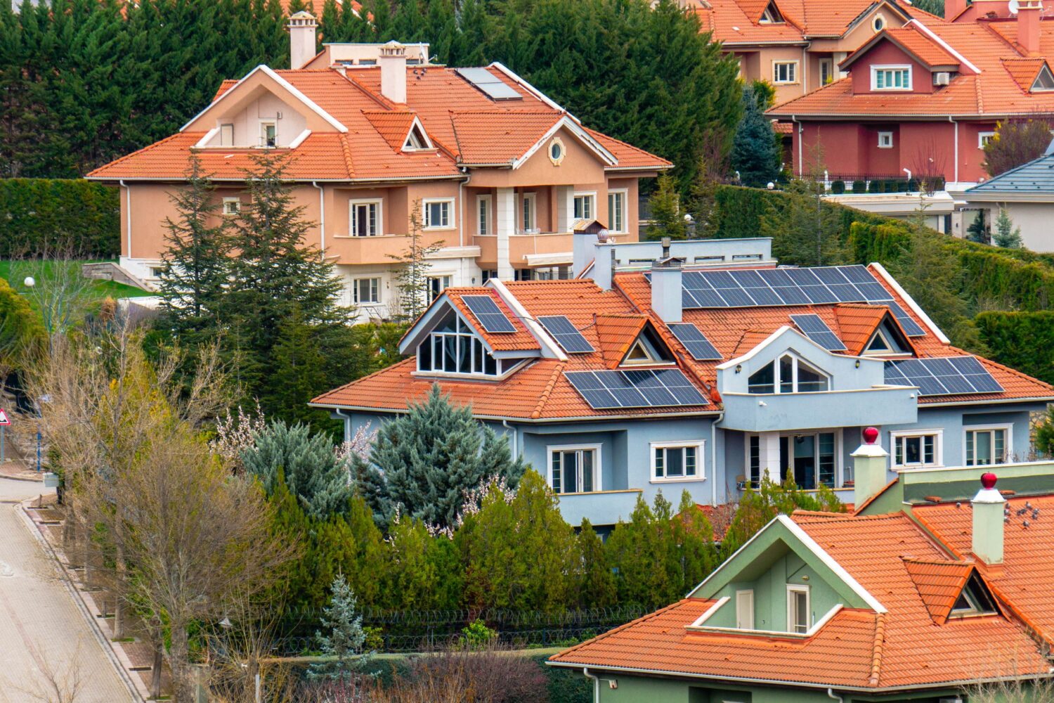 Beautiful homes in Ankara with solar panels, showcasing eco-friendly architecture surrounded by lush gardens.
