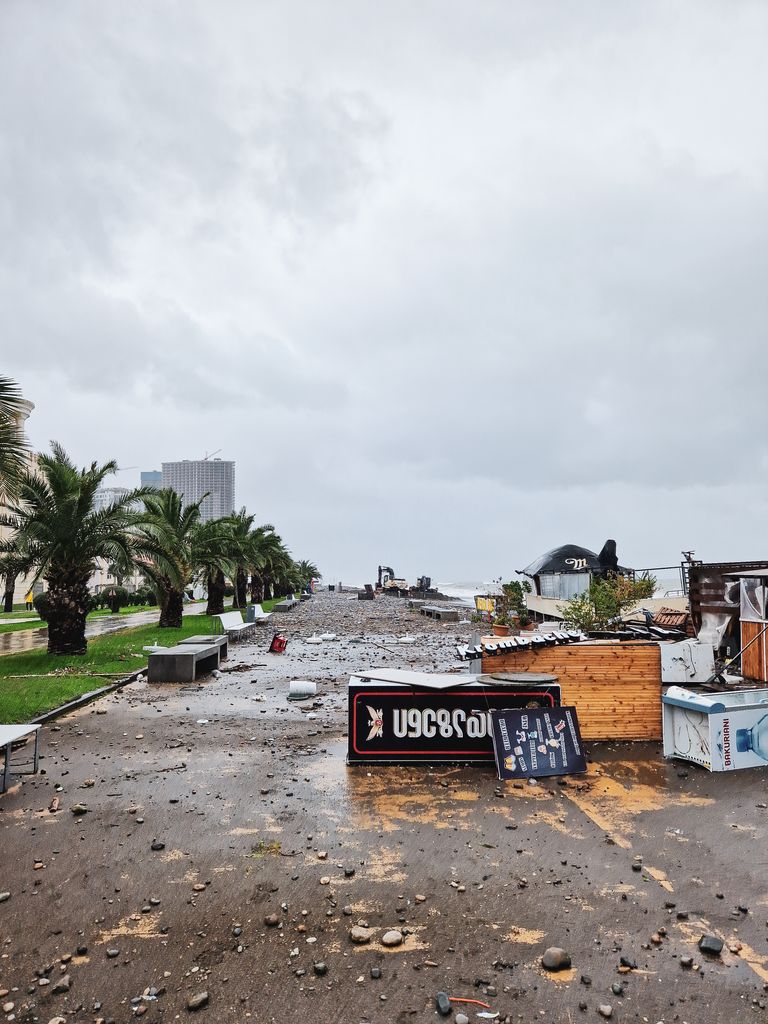 Destruction on a city street after a severe storm with fallen signs and debris.